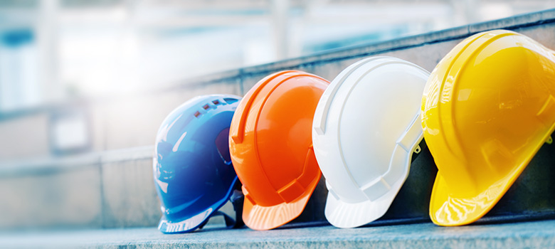 Four industrial safety helmets, in different colors, lying on a staircase