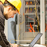 Vorausschauender Kundenservice im digitalen Zeitalter Mitarbeiter mit Schutzhelm am Laptop an der Maschine